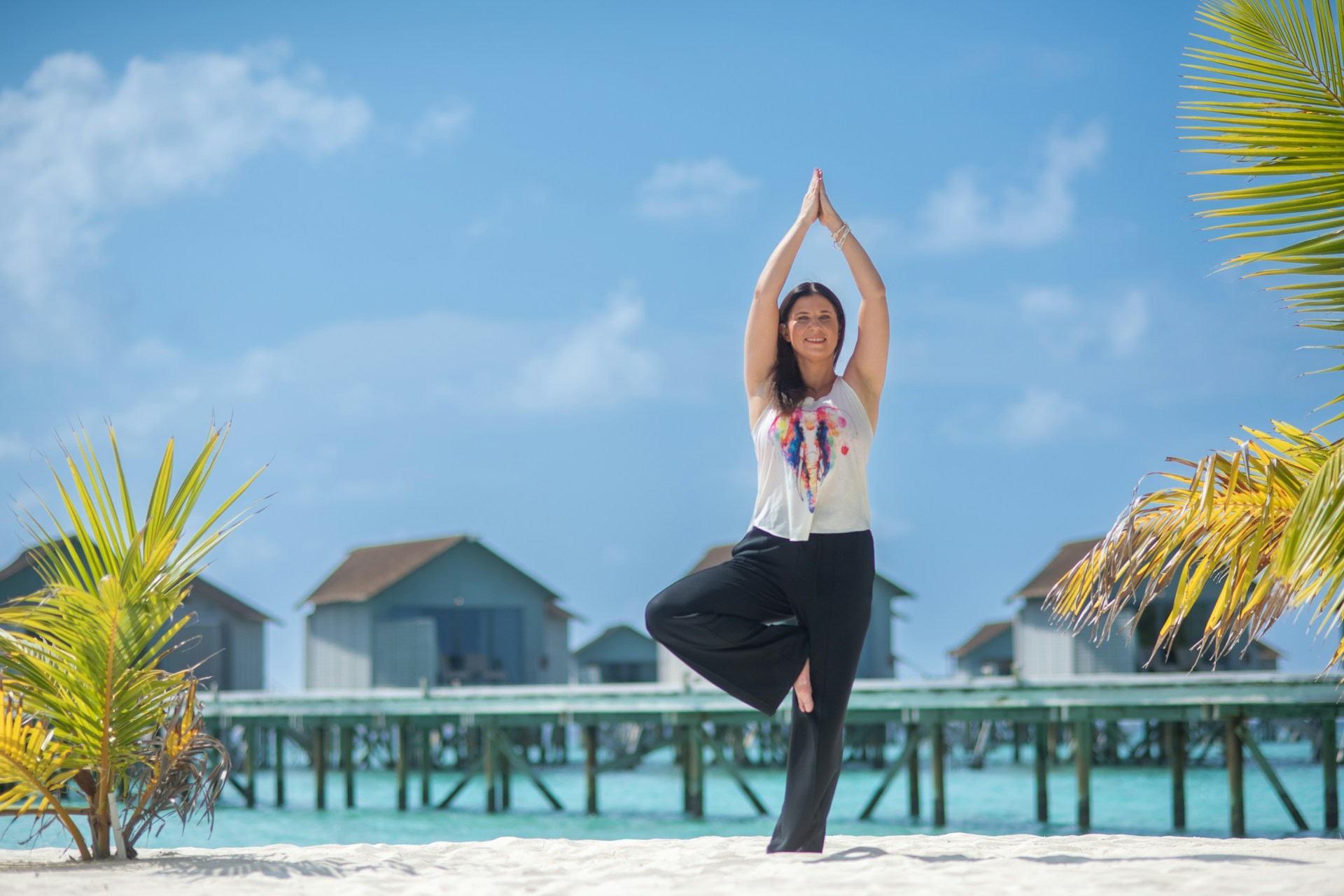 Young woman performing yoga at a beach, demonstrating the peace and serenity of wellness travel.