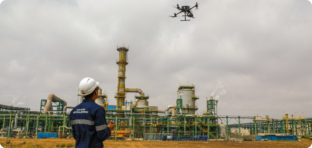 Technician using a drone for industrial inspection and condition monitoring at a manufacturing plant to improve safety and predictive maintenance.