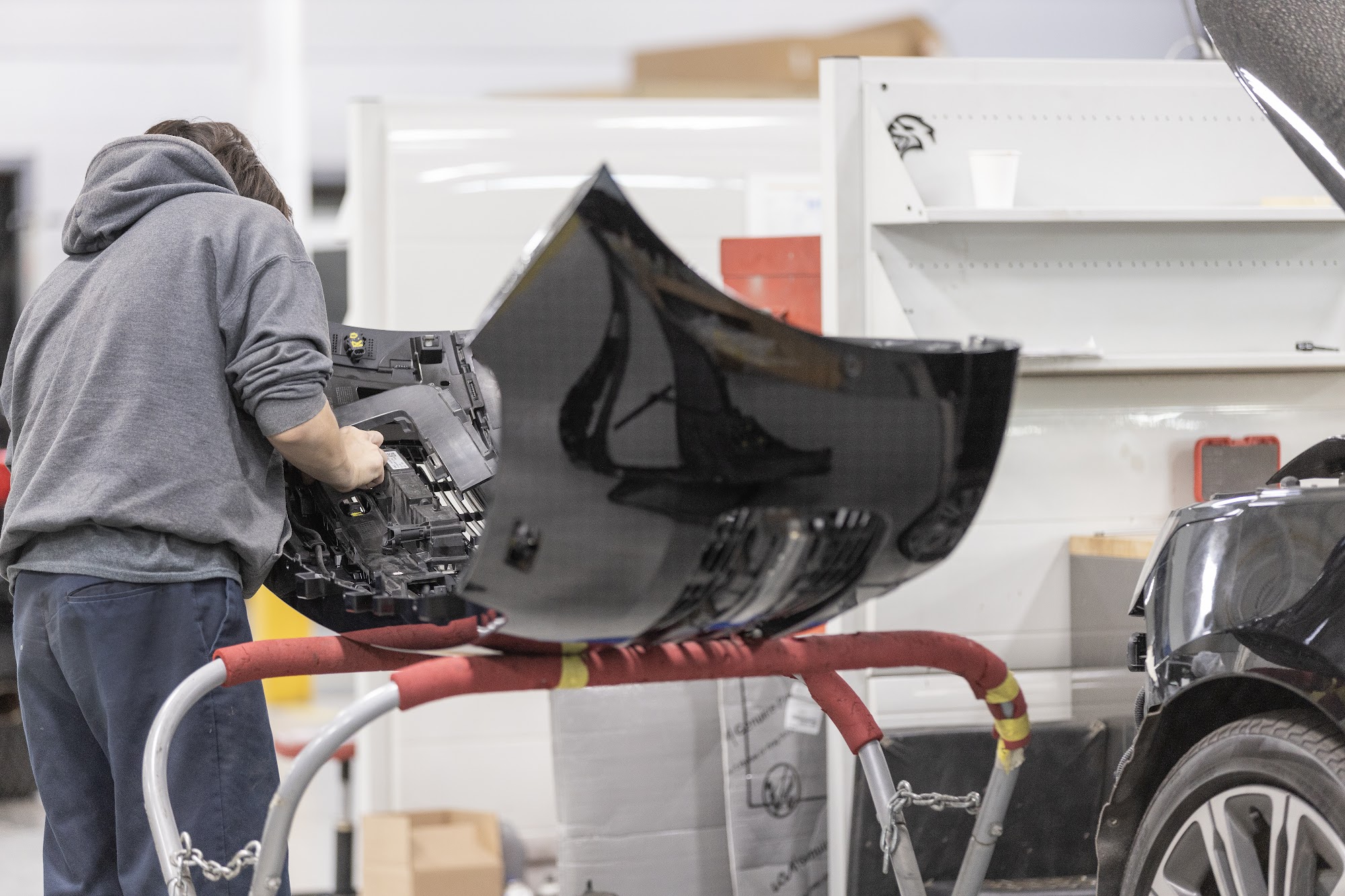 A CSN 427 Auto technician fits components on a removed bumper cover during the repair planning stage