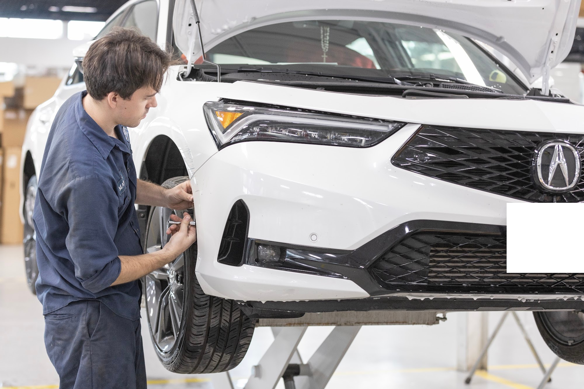 A CSN 427 Auto technician inspects the front bumper corner of a white Acura