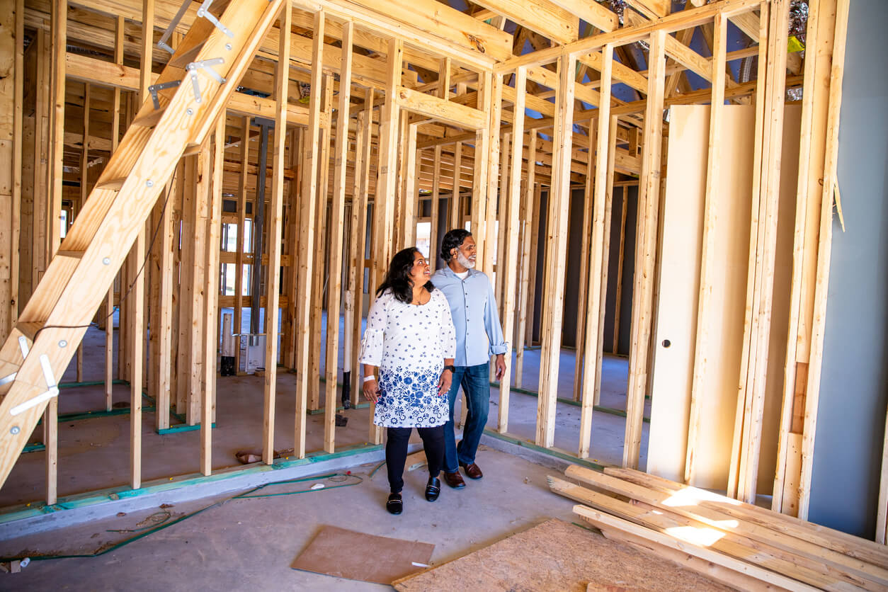 Two new homeowners walk through their construction site during the framing stage of a rebuild.