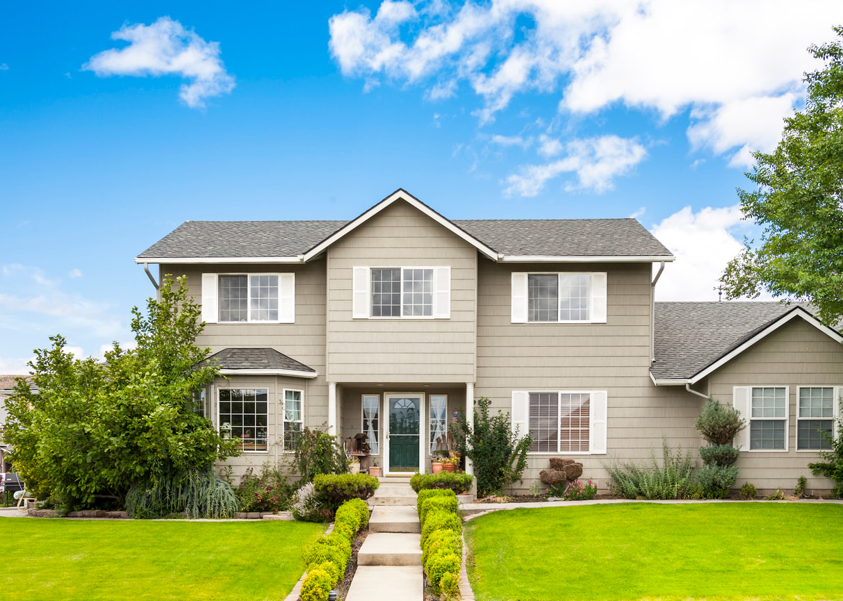 A photo of a beautiful and well-kept home next to a green lawn.