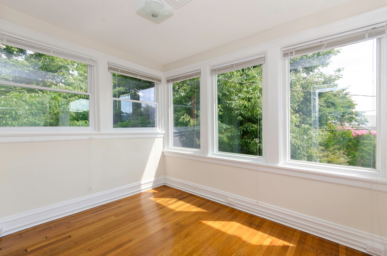 A photo showing a room with hard wood floors and several large windows.