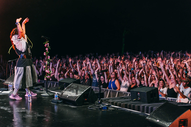 singer on stage with hands up 