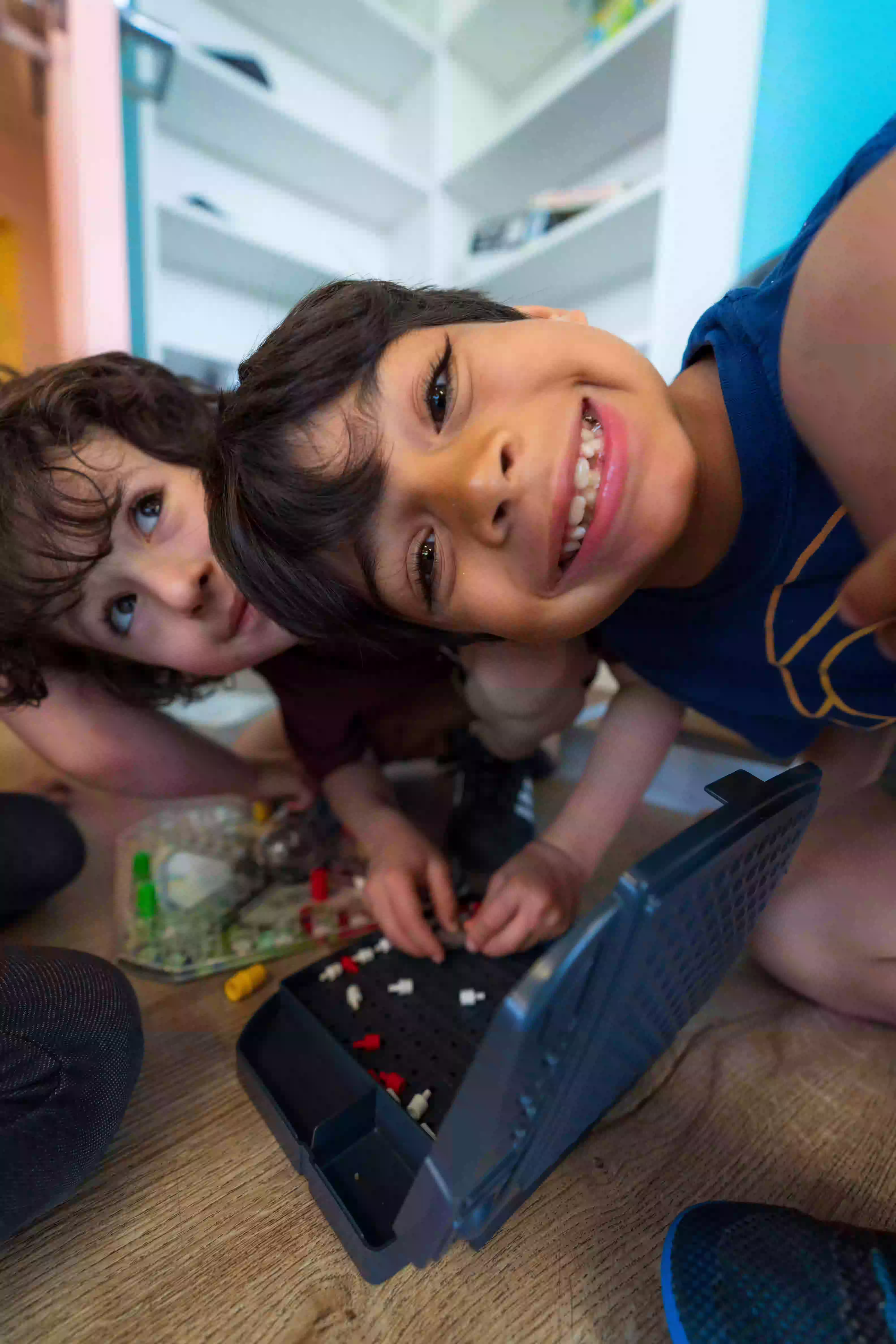 Two boys playing with building blocks on the floor.
