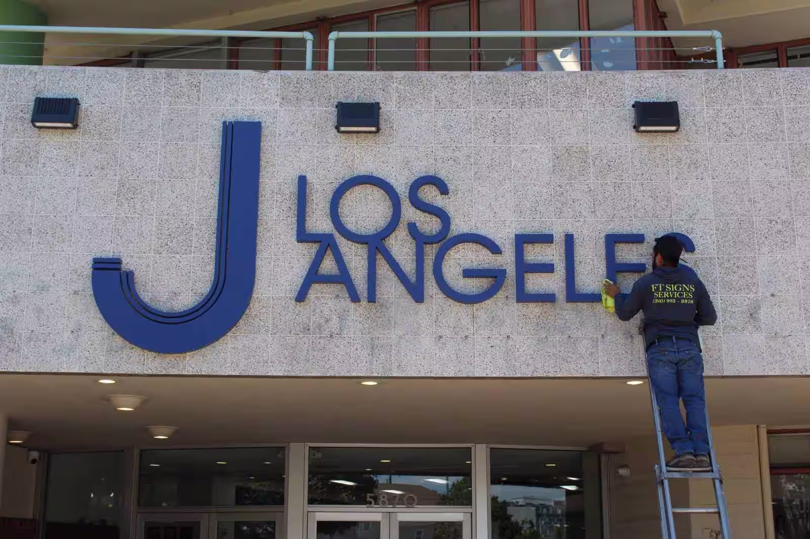 Worker installing sign for J Los Angeles, Jewish Community Center.