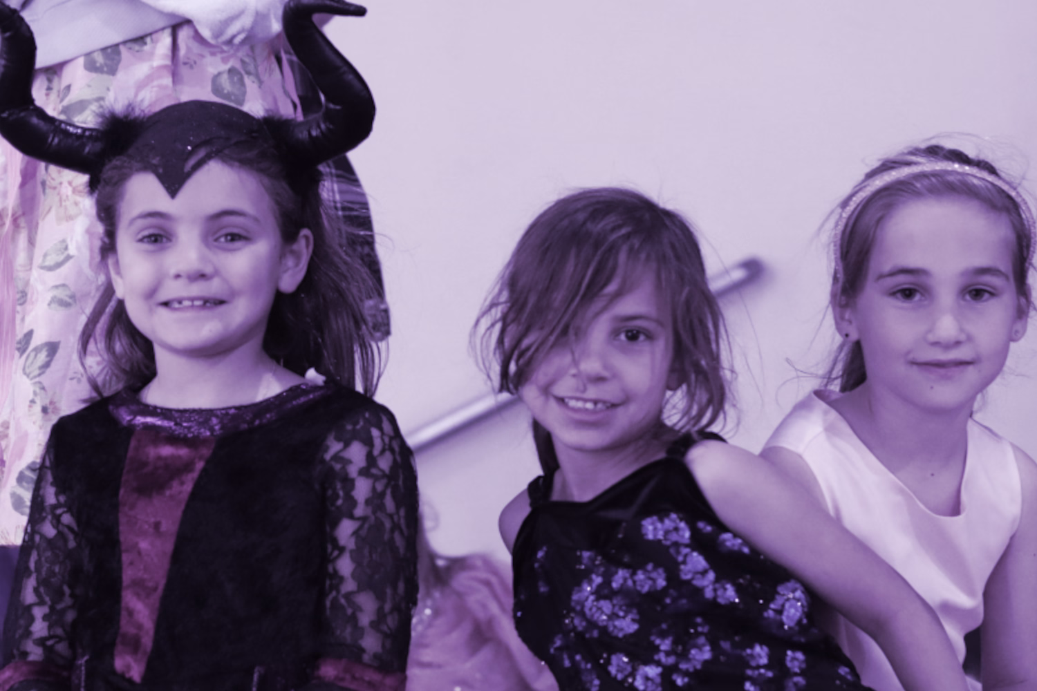 Three girls in costumes smiling together.