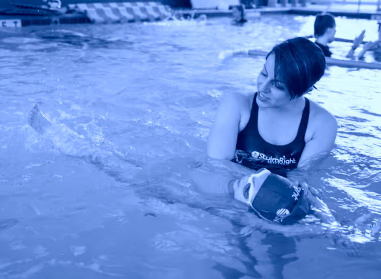 Swimming instructor assisting a child in a pool. Membership at the local Jewish Community Center.