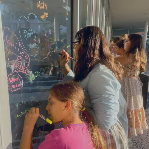 Children writing on glass windows during an event for Jewish High Holidays Los Angeles Services Programs for Children 5786.