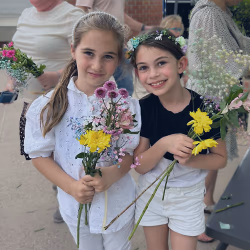 Two girls holding flower bouquets at an event.