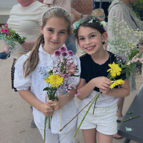 Two girls holding flower bouquets at an event.