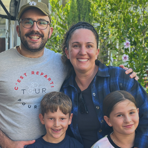Group photo of adults and children smiling together outdoors.
