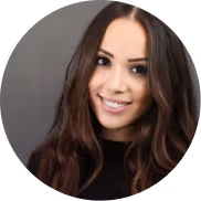 Portrait of a smiling woman with long brown hair against a gray background.
