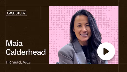 Portrait of Maia Calderhead, HR head at AAG, smiling with long dark hair and wearing a gray blazer against a pink dotted background with a play button overlay.