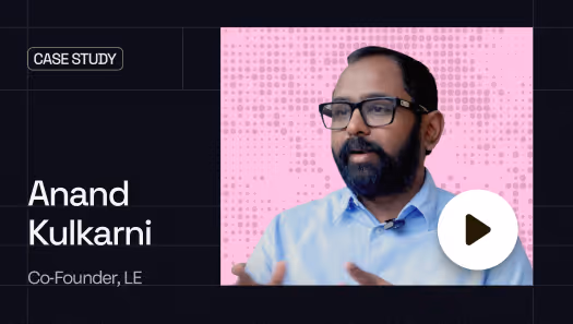Portrait of Anand Kulkarni, Co-Founder of LE, wearing glasses and a blue shirt with a play button overlay.