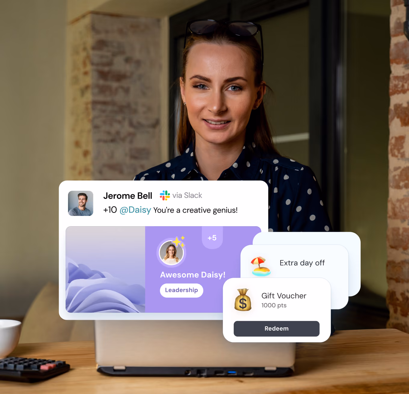 Smiling woman with glasses on her head sits at a table with a laptop, with floating digital graphics showing a Slack message praising 'Daisy' as a creative genius, and reward options including extra day off and a gift voucher redeemable for points.