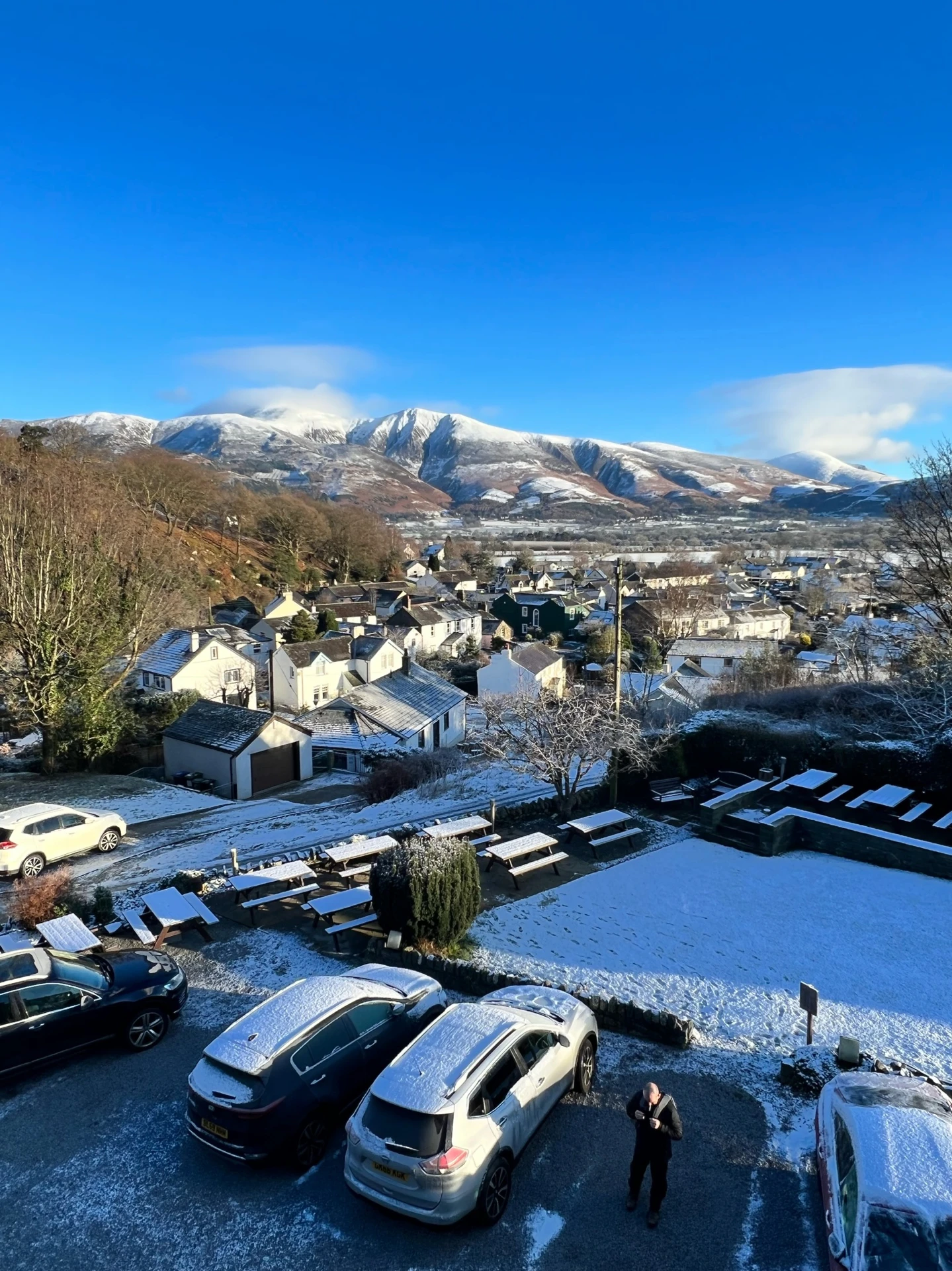 The snowy village of Braithwaite Village in Keswick with rolling snowy mountains in the distance.