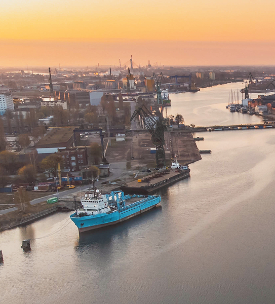 Gdańsk Shipyard, Poland with port cranes and cargo vessel on the Motława River at sunrise (Gdańsk maritime port infrastructure)