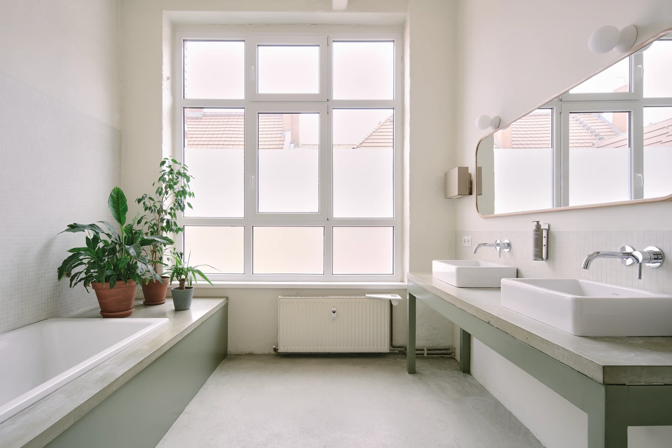 A close up of the bordered bathtub with wood paneling and concrete top plate accompanied by houseplants near the large window