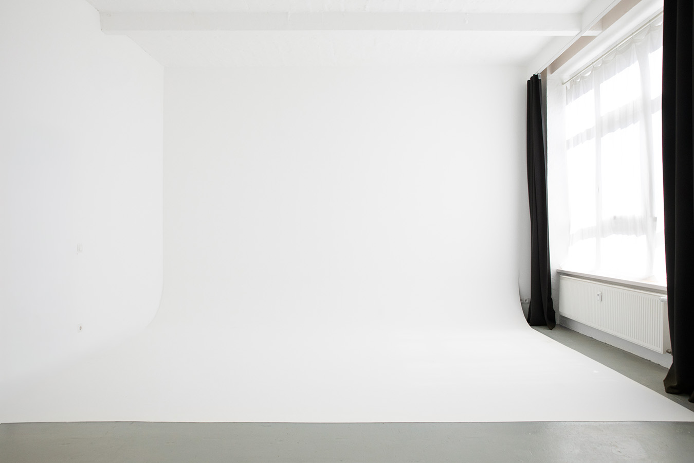 Kompaktes Fotostudio in Berlin mit einer professionellen weißen Hohlkehle, Industriebetonboden und großen Fenstern im Studio 2B.
