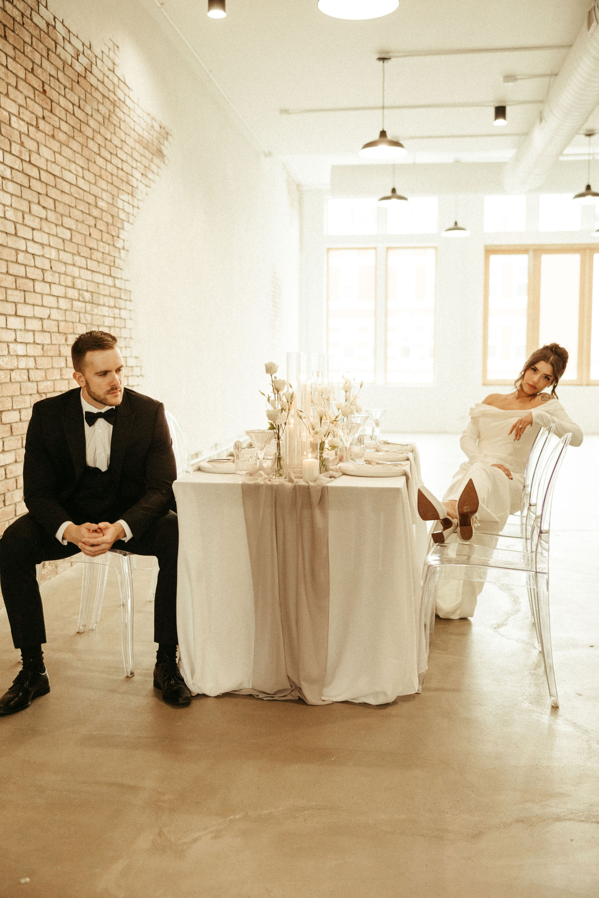 A bride and groom sit wth a beautifully decorated table in a brightly lit Edmonton Wedding Venue  