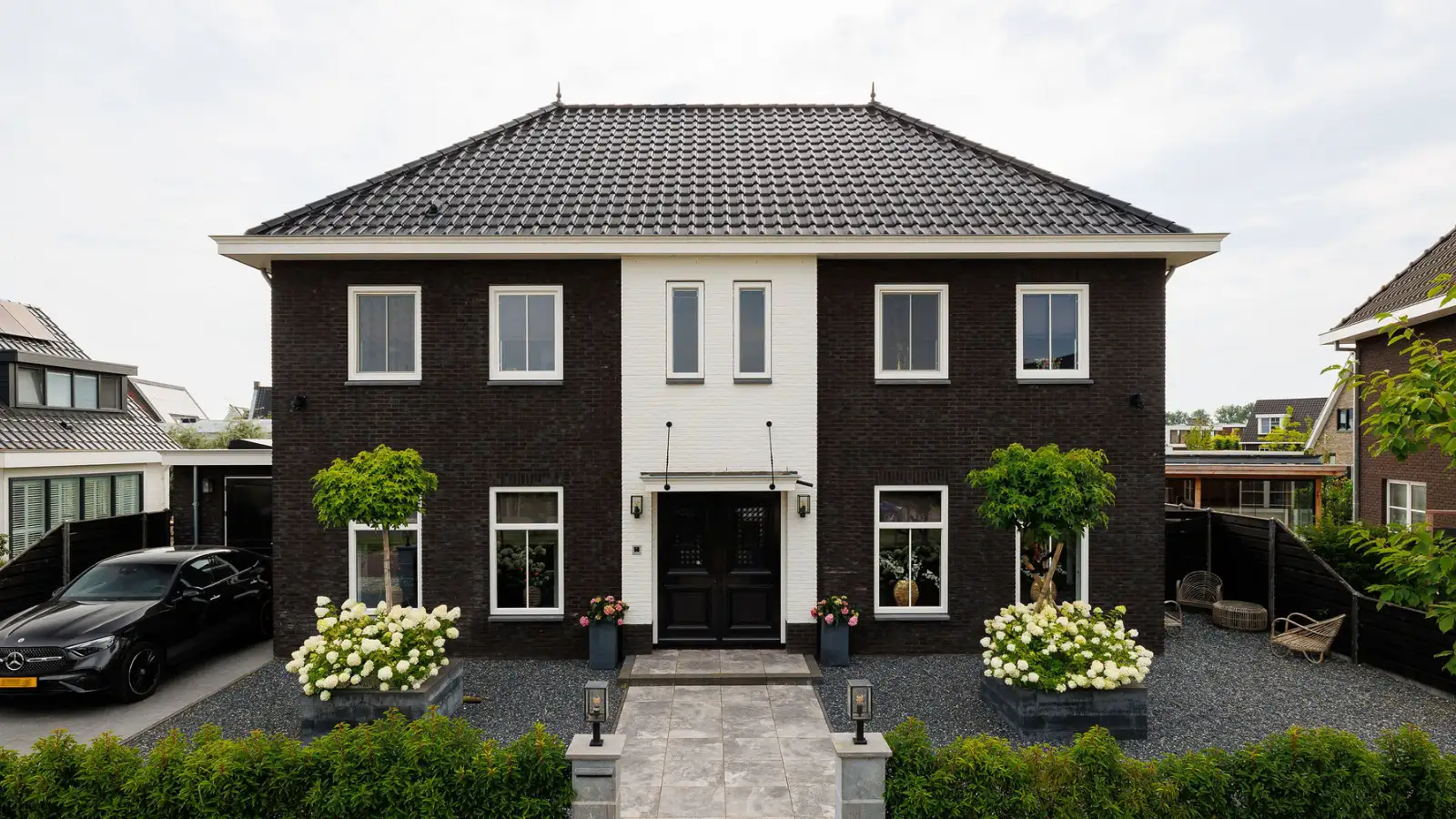 Vooraanzicht van een statig herenhuis met zwarte gevelstenen en wit gecentreerd risaliet