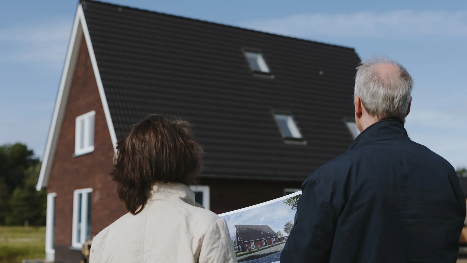 Man en vrouw staan met een render in de hand te kijken naar hun woning in aanbouw