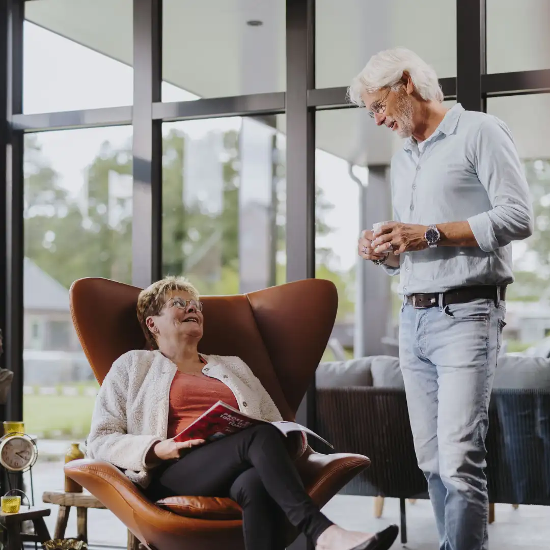 Ouder echtpaar zijn met elkaar in gesprek in de woonkamer