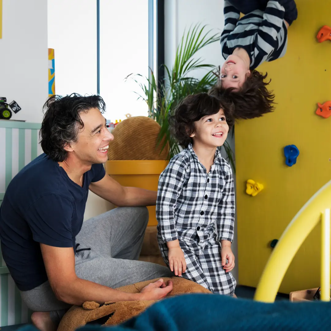 Vader en twee zoons zijn aan het spelen in de woonkamer