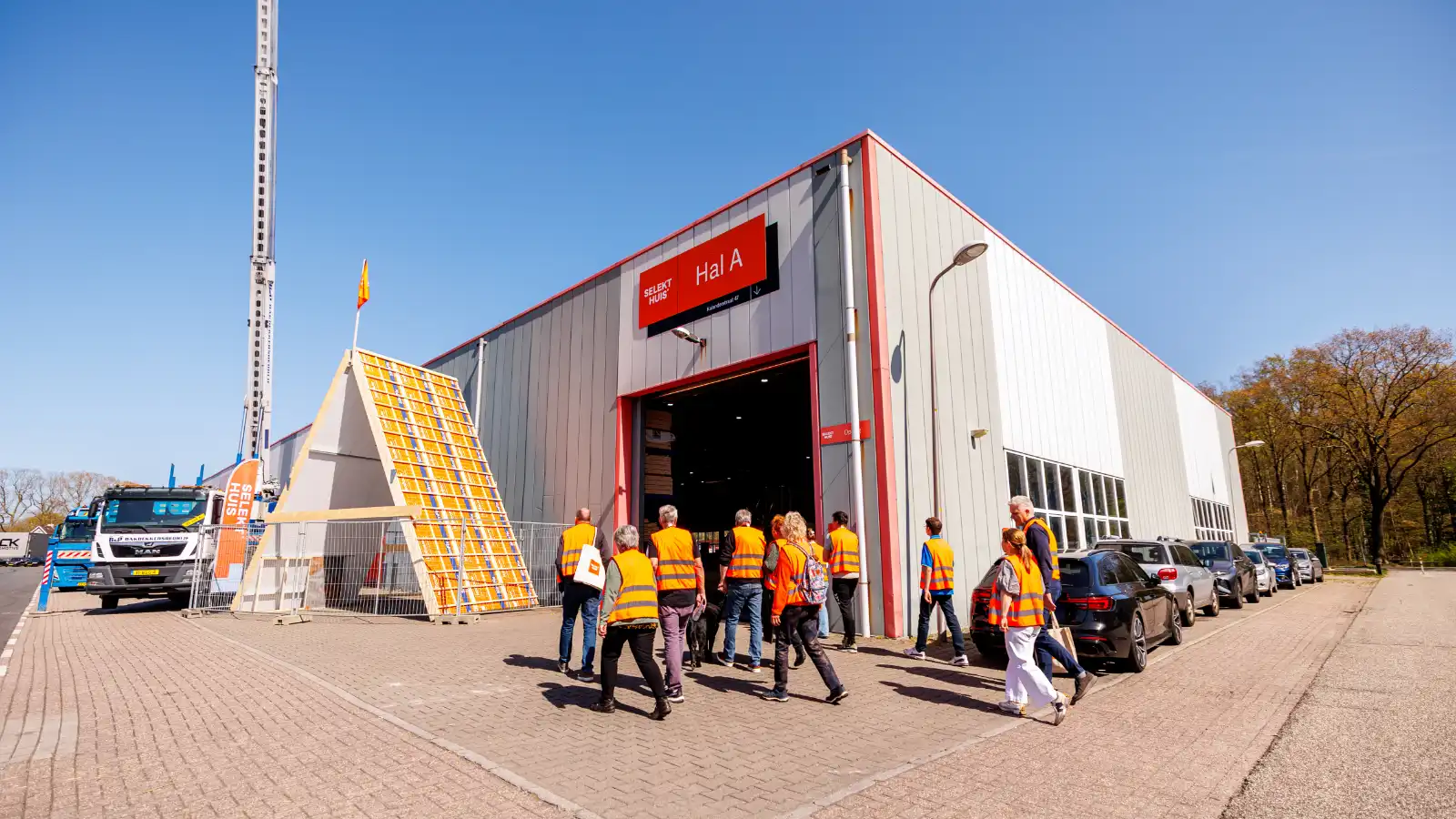 Groep mensen met oranje hesjes staat loopt een grote hal binnen