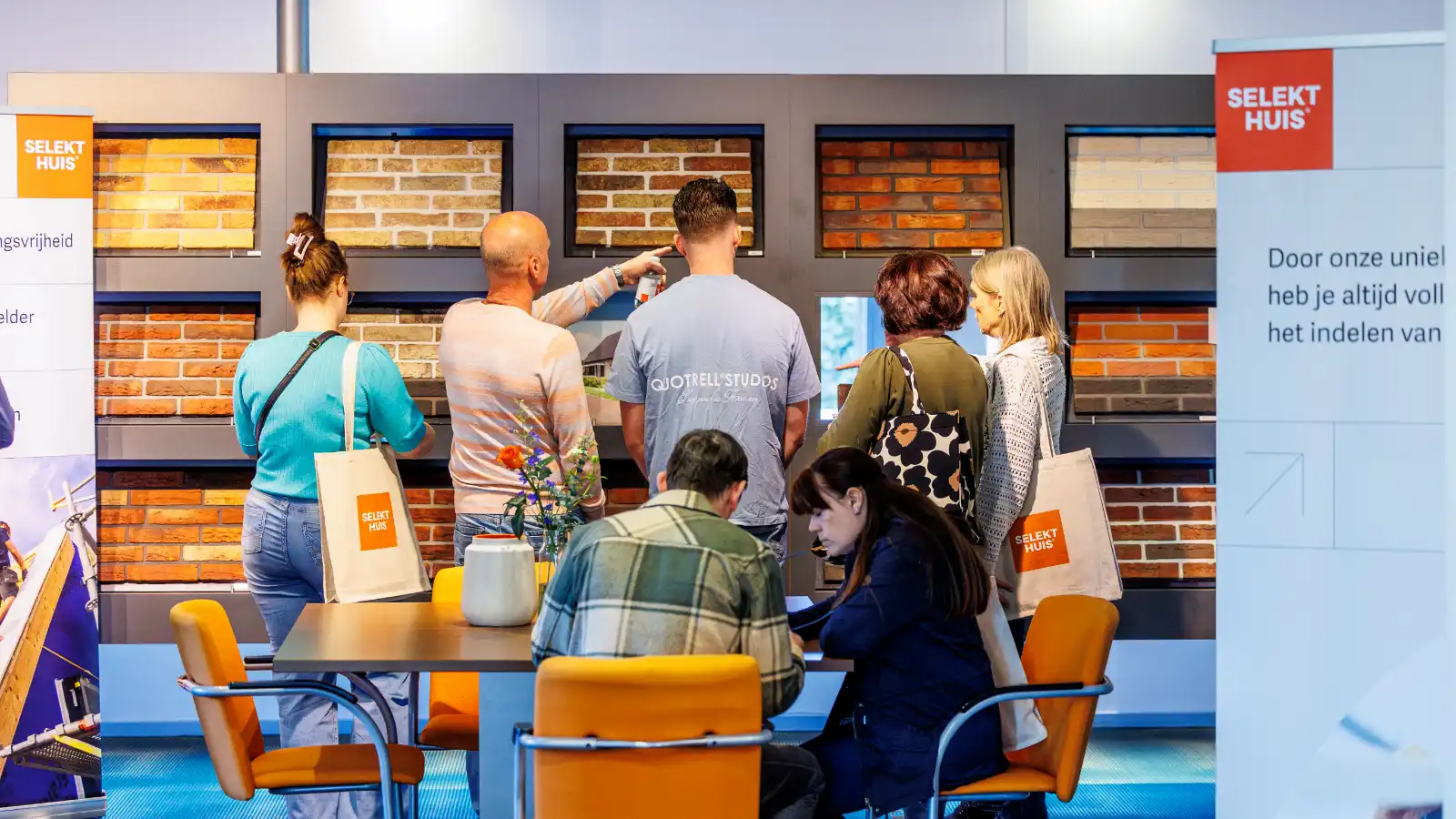 Een groepje mensen staat te kijken bij verschillende gevelstenen in een showroom