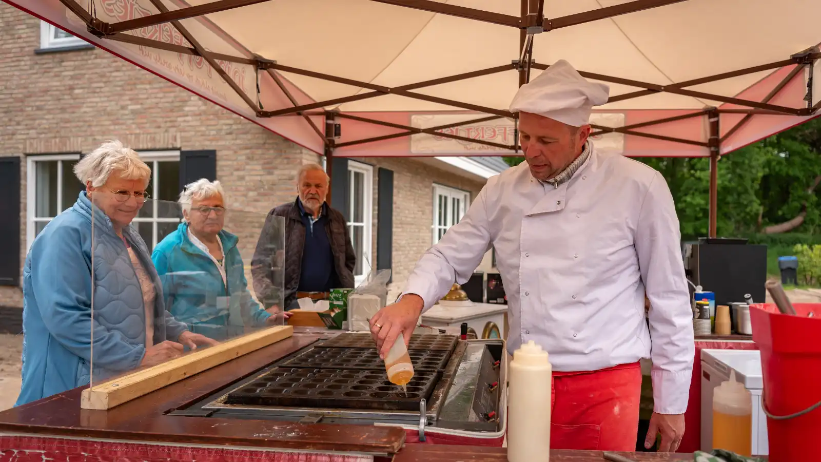 Iemand met kokskleding bakt poffertjes