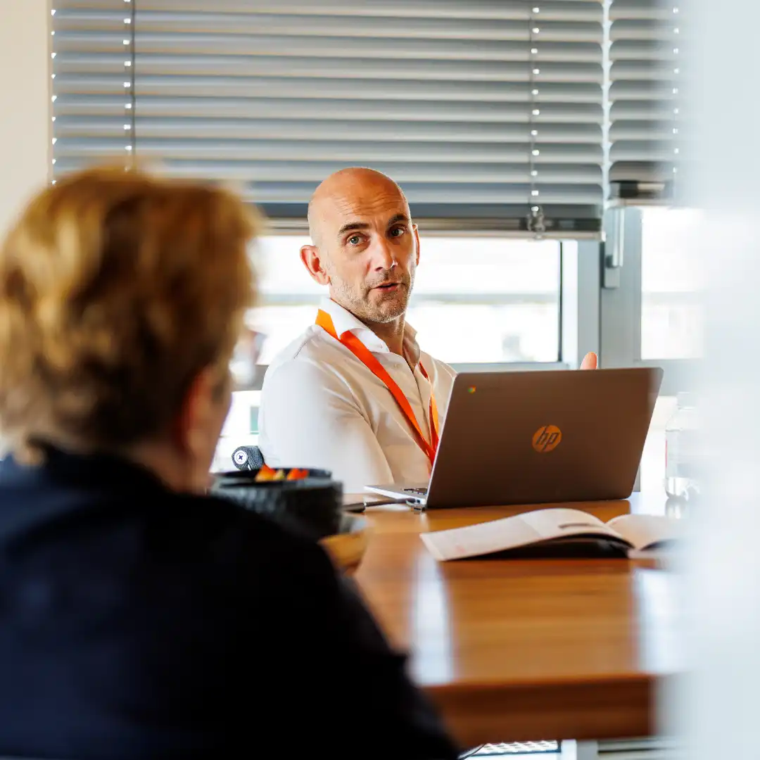 Een adviseur van SelektHuis met laptop in gesprek met een klant