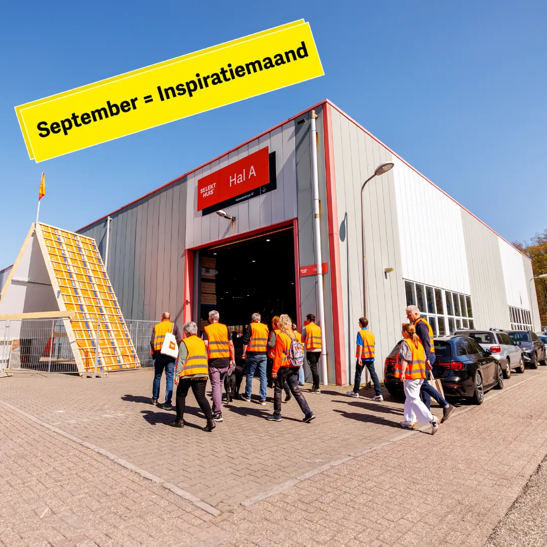 Een groep mensen met veiligheidshesje aan lopen een grote hal in