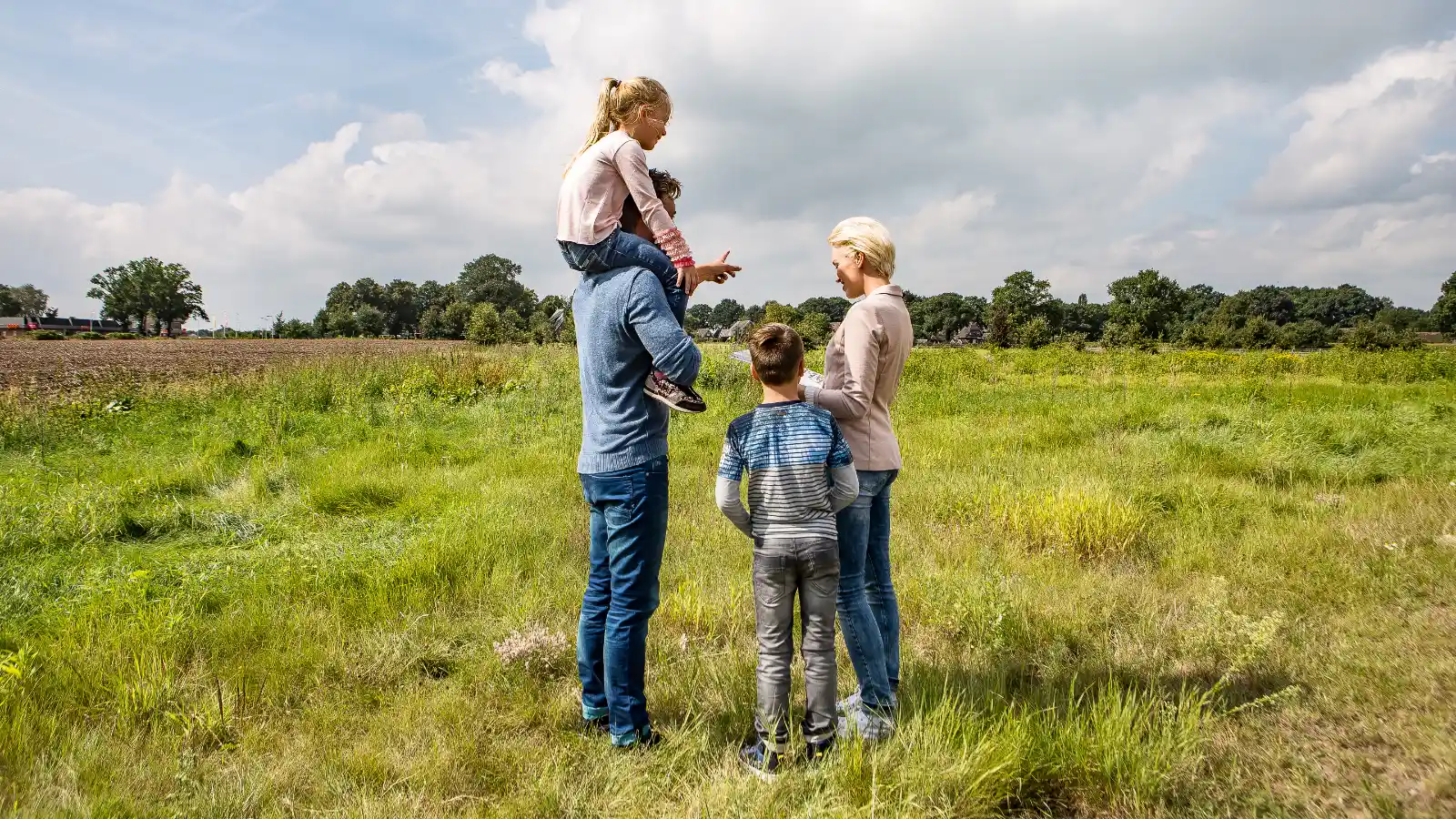 Een gezin staat samen op een groen grasveld