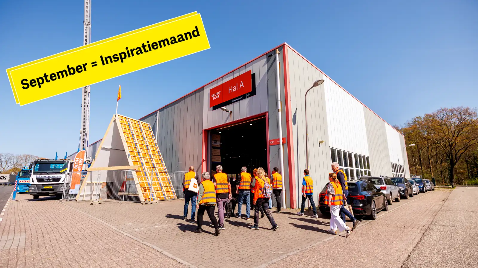 Groep mensen met oranje hesjes staat loopt een grote hal binnen
