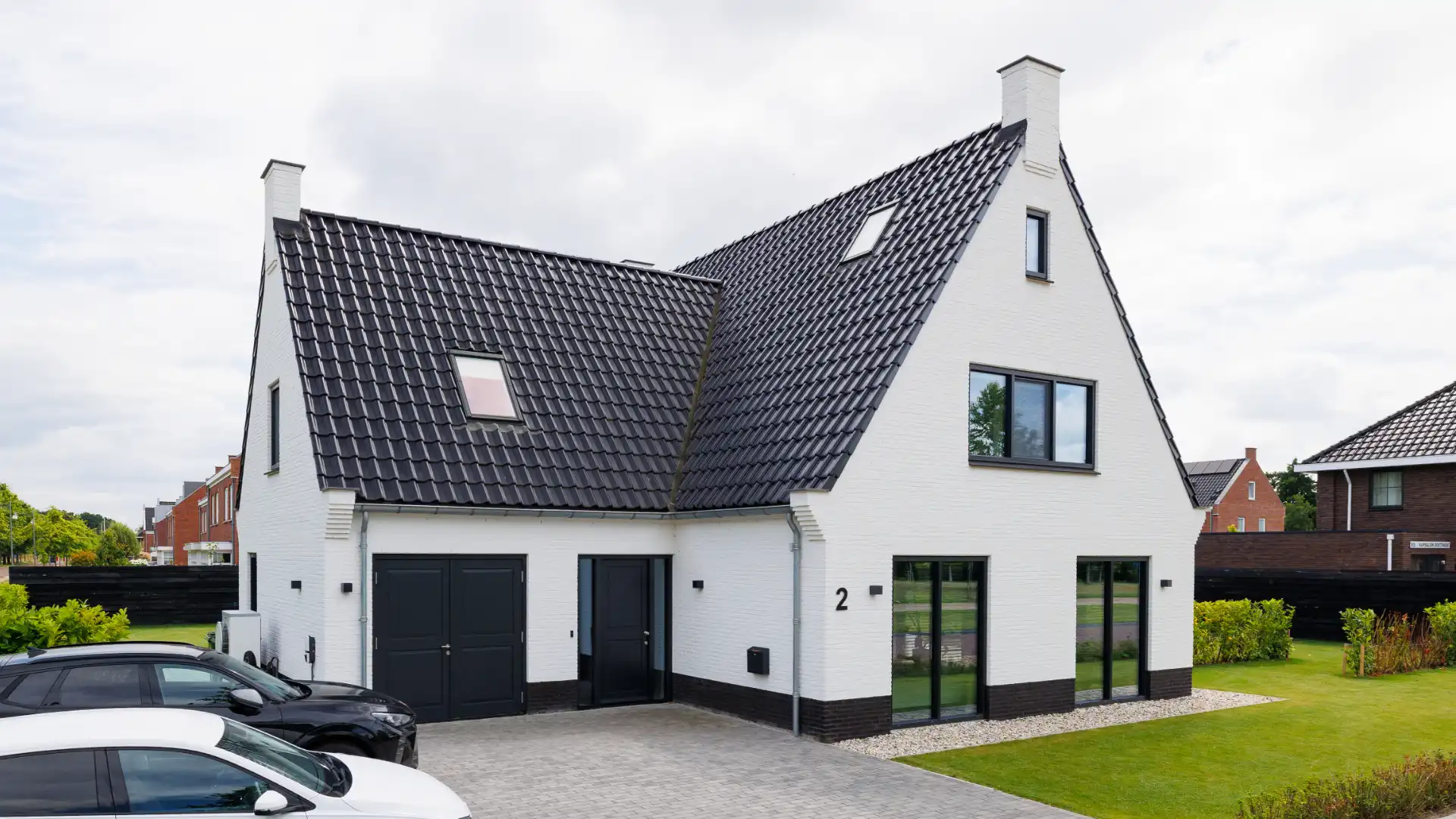 Vooraanzicht van een witte vrijstaande woning met aanbouw