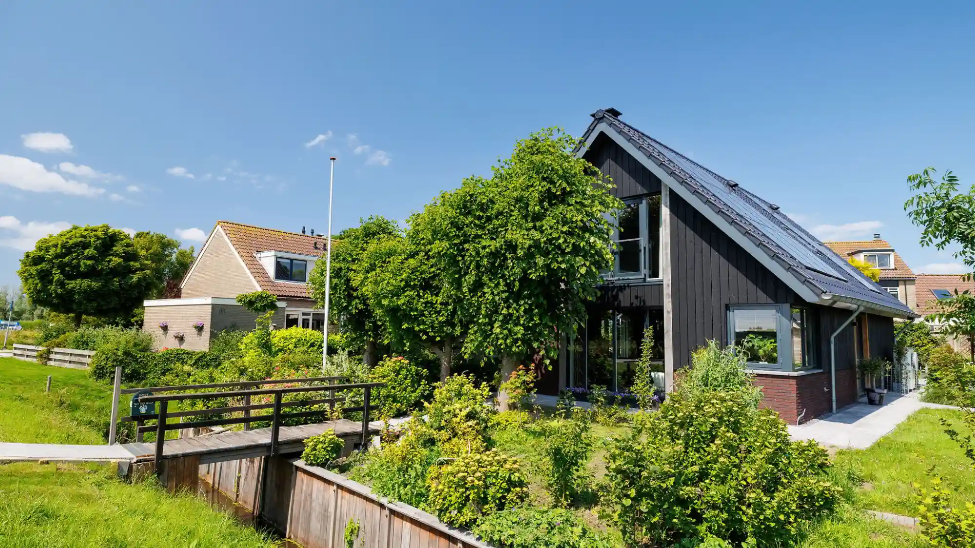 Zwarte schuurwoning met bruggetje in voortuin