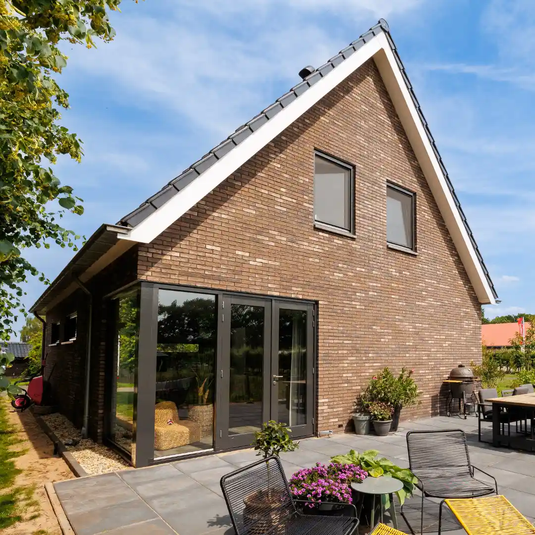 Zijaanzicht moderne landelijk gezinswoning met donker hoekkozijn