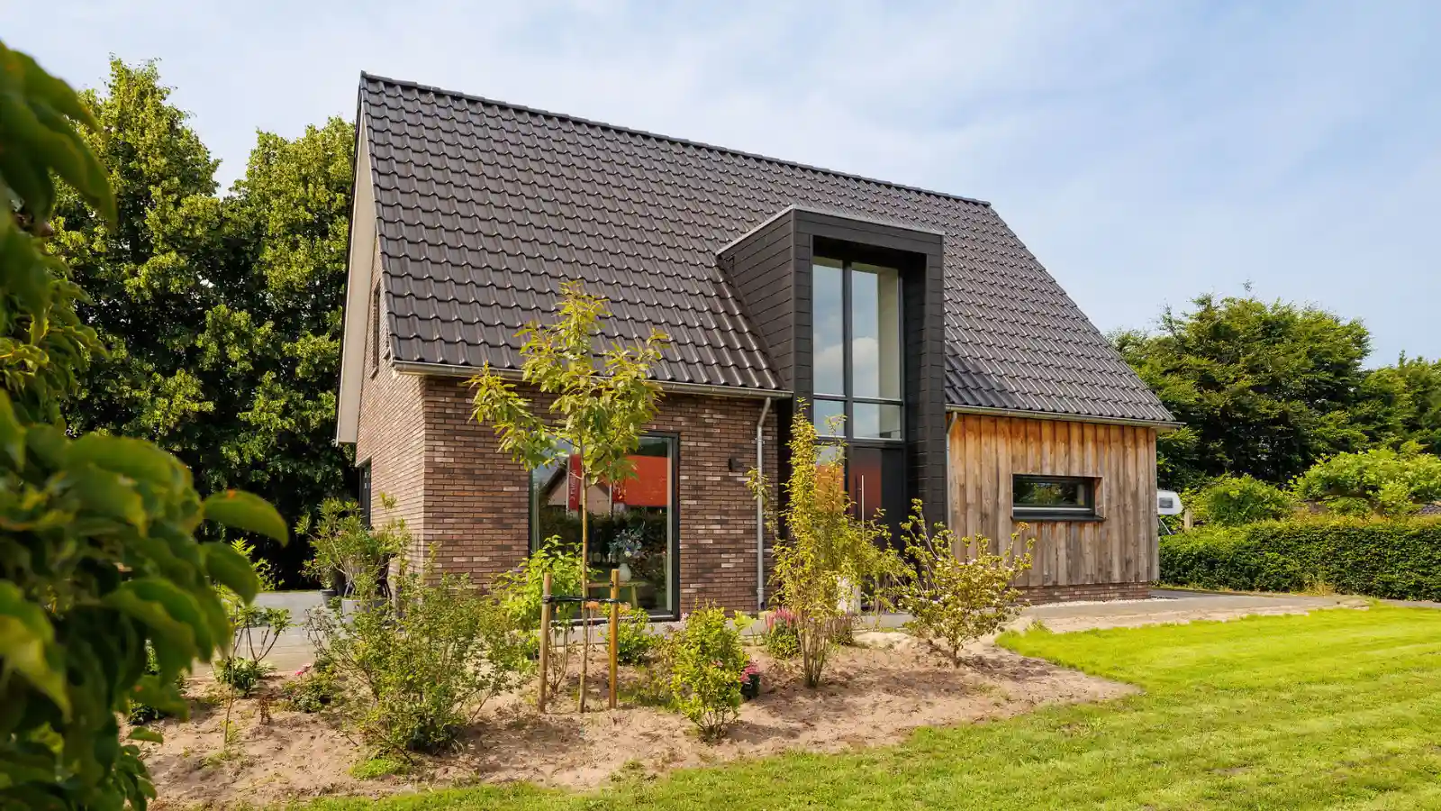 Zijaanzicht moderne landelijk gezinswoning met risaliet en houten gevelbekleding