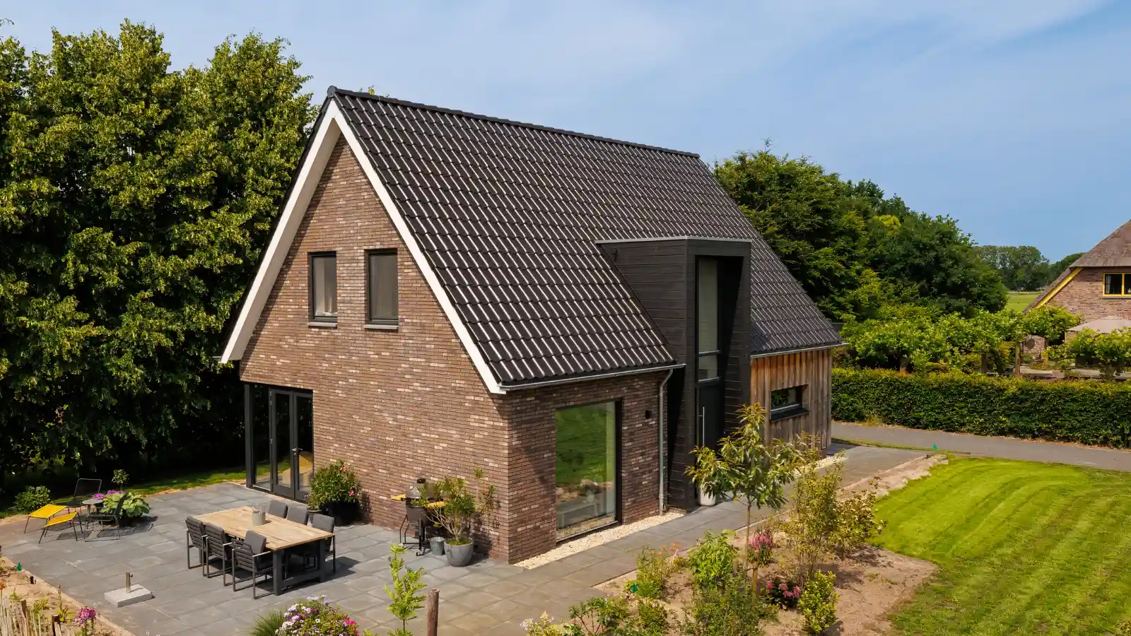 Zijkant van vrijstaande woning met pannendak en houten risaliet