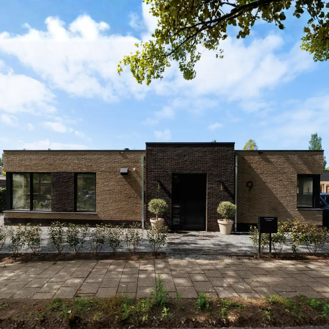 Vooraanzicht bungalow met donkere stenen rondom de voordeur