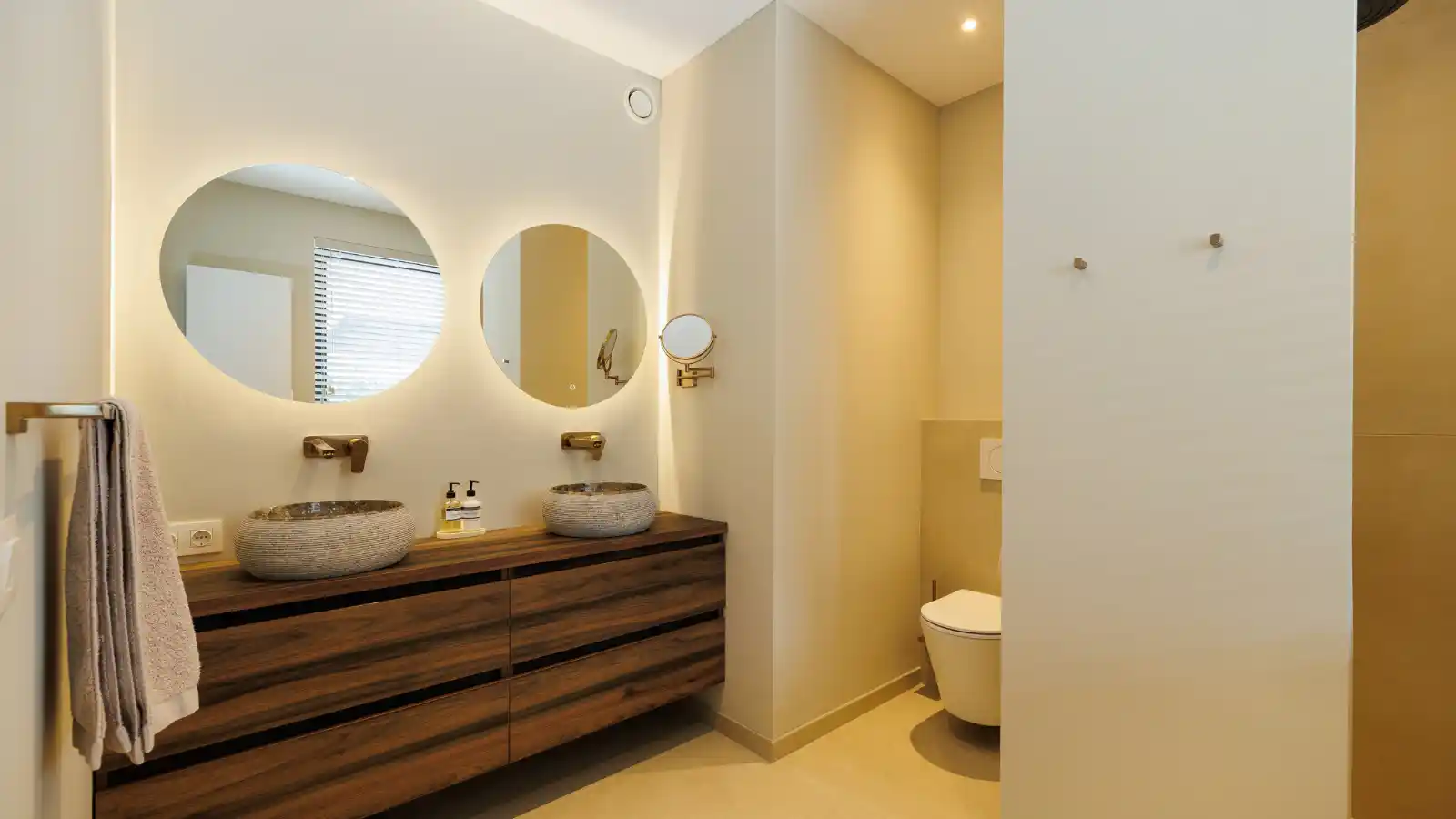 Badkamer met houten badmeubel en 2 ronde spiegels