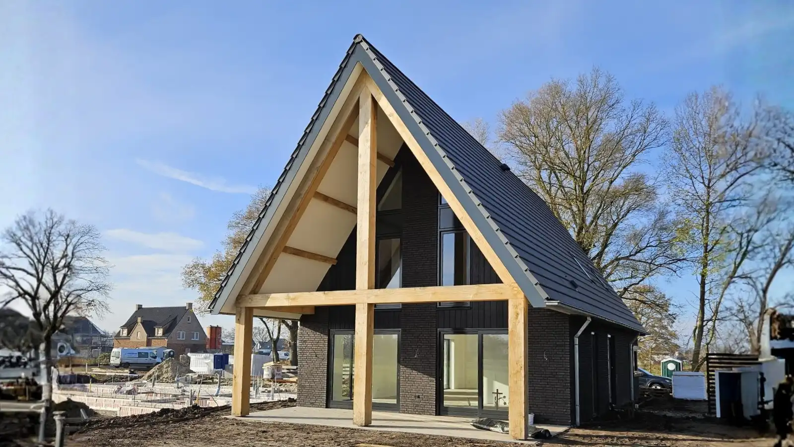 Vrijstaande woning met overkapping en houten gebinten en donkere stenen.