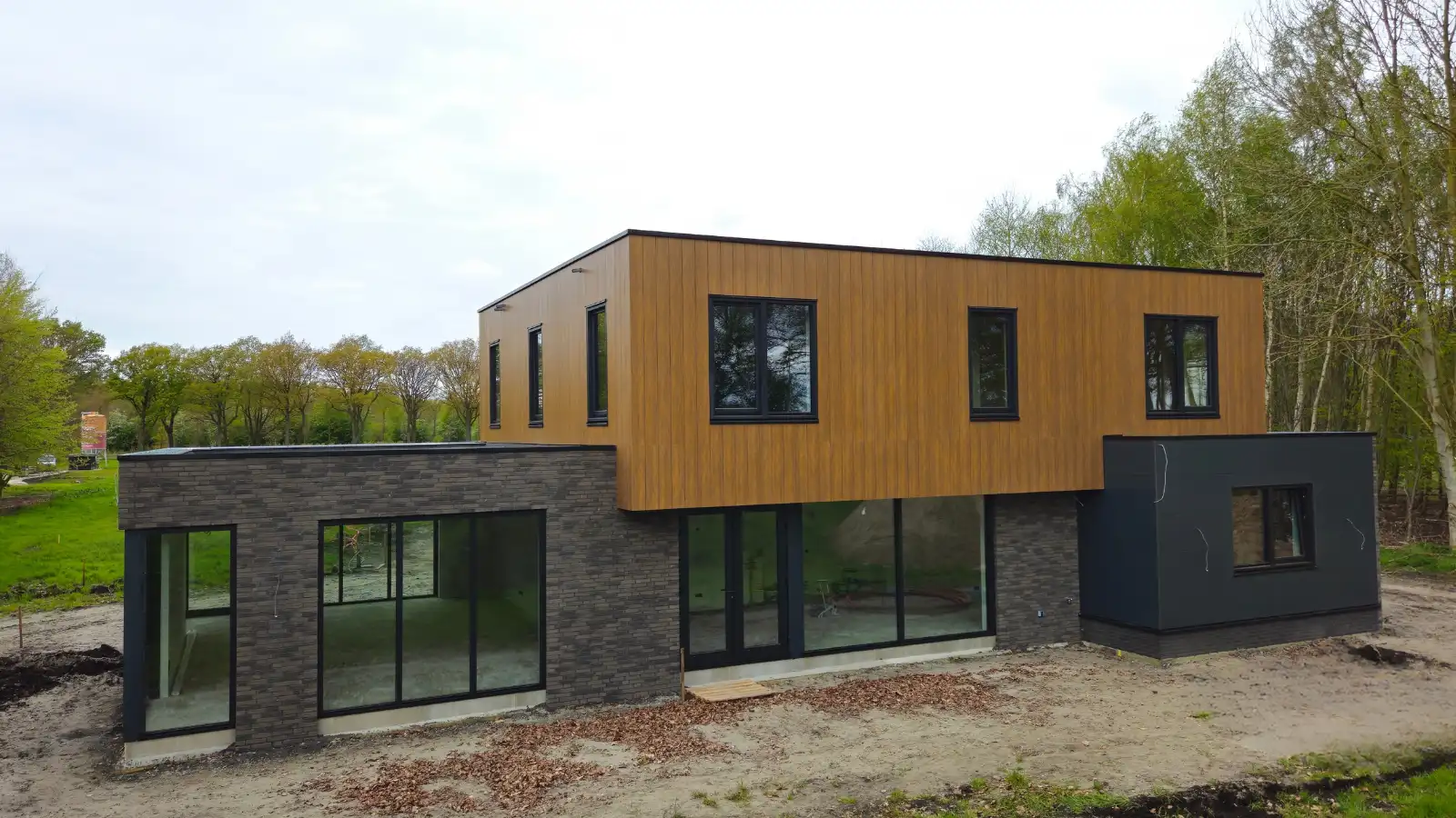 Vrijstaande woning met plat dak. Donkere gevelstenen en houten gevelbekleding
