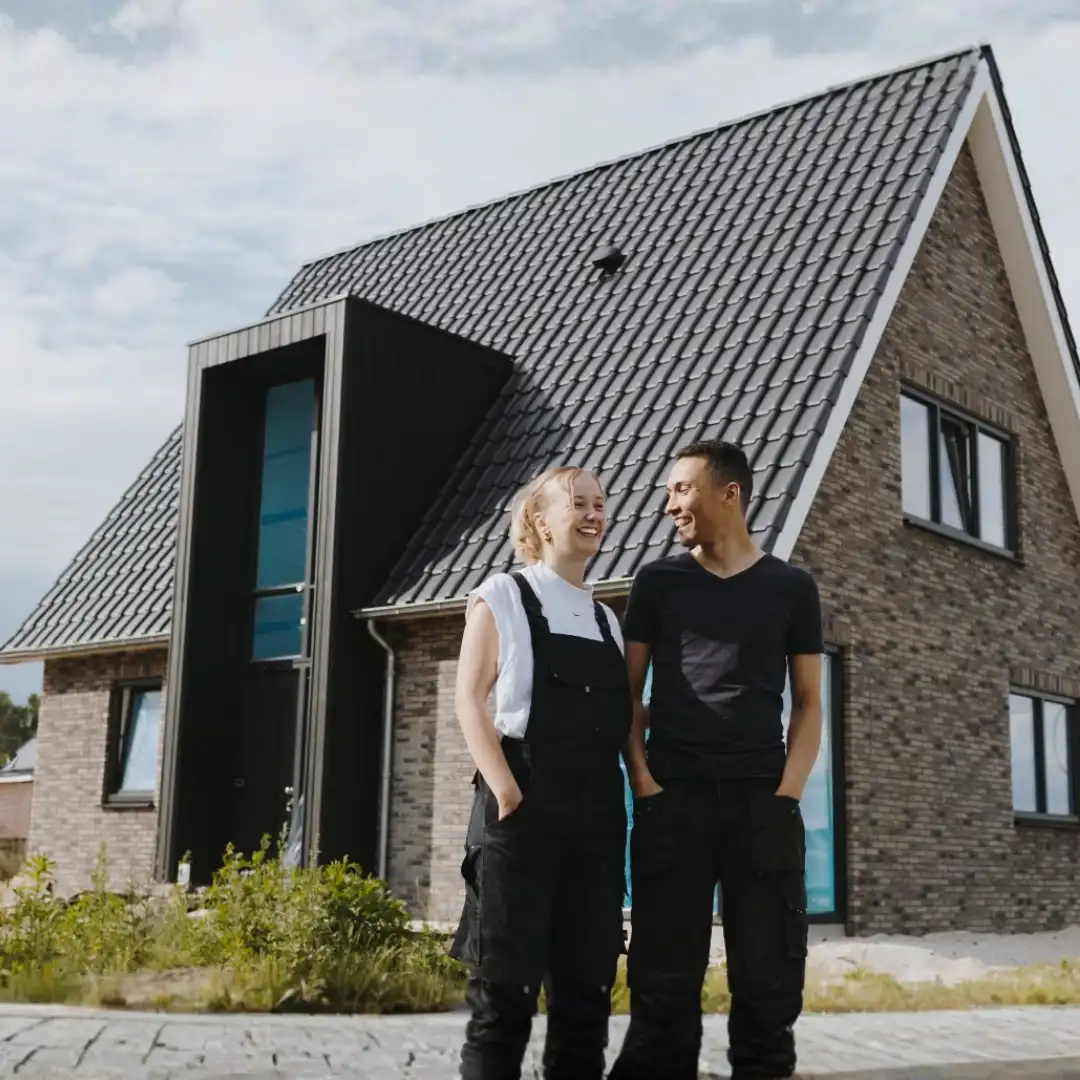 Man en vrouw staan voor huis nieuwe vrijstaande woning in aanbouw