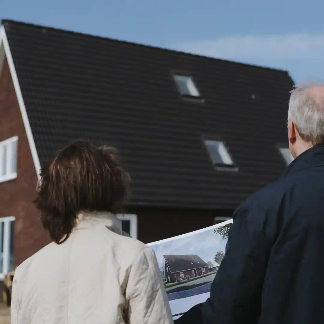 Man en vrouw staan voor huis tekening van woning in de hand