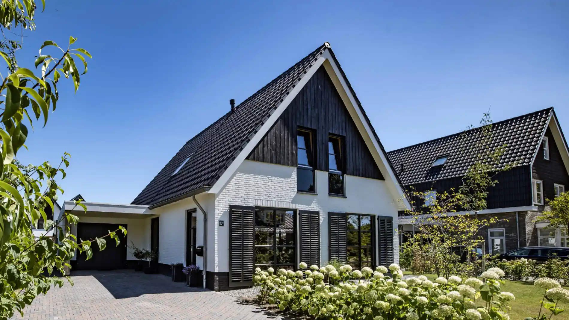 Vrijstaande woning met witte stenen en zwart houten gevelbekleding