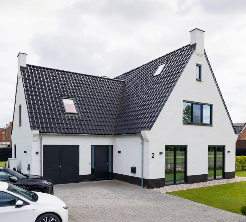 Vooraanzicht van een witte vrijstaande woning met aanbouw