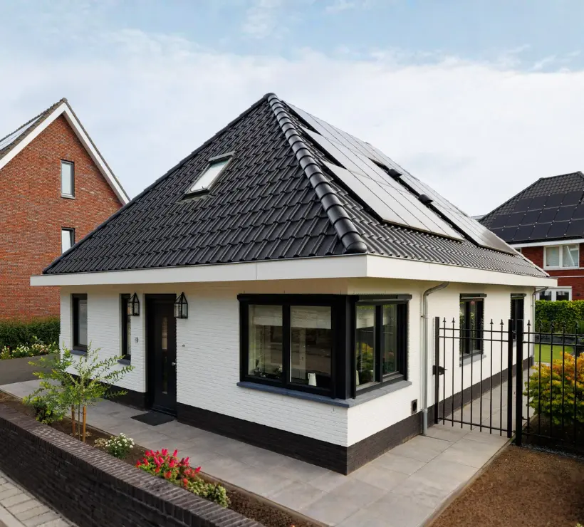 Vooraanzicht van een witte vrijstaande woning met zwarte kozijnen